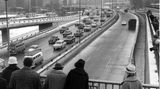 Schaulustige betrachten von einer Brücke aus eine neue Autobahn