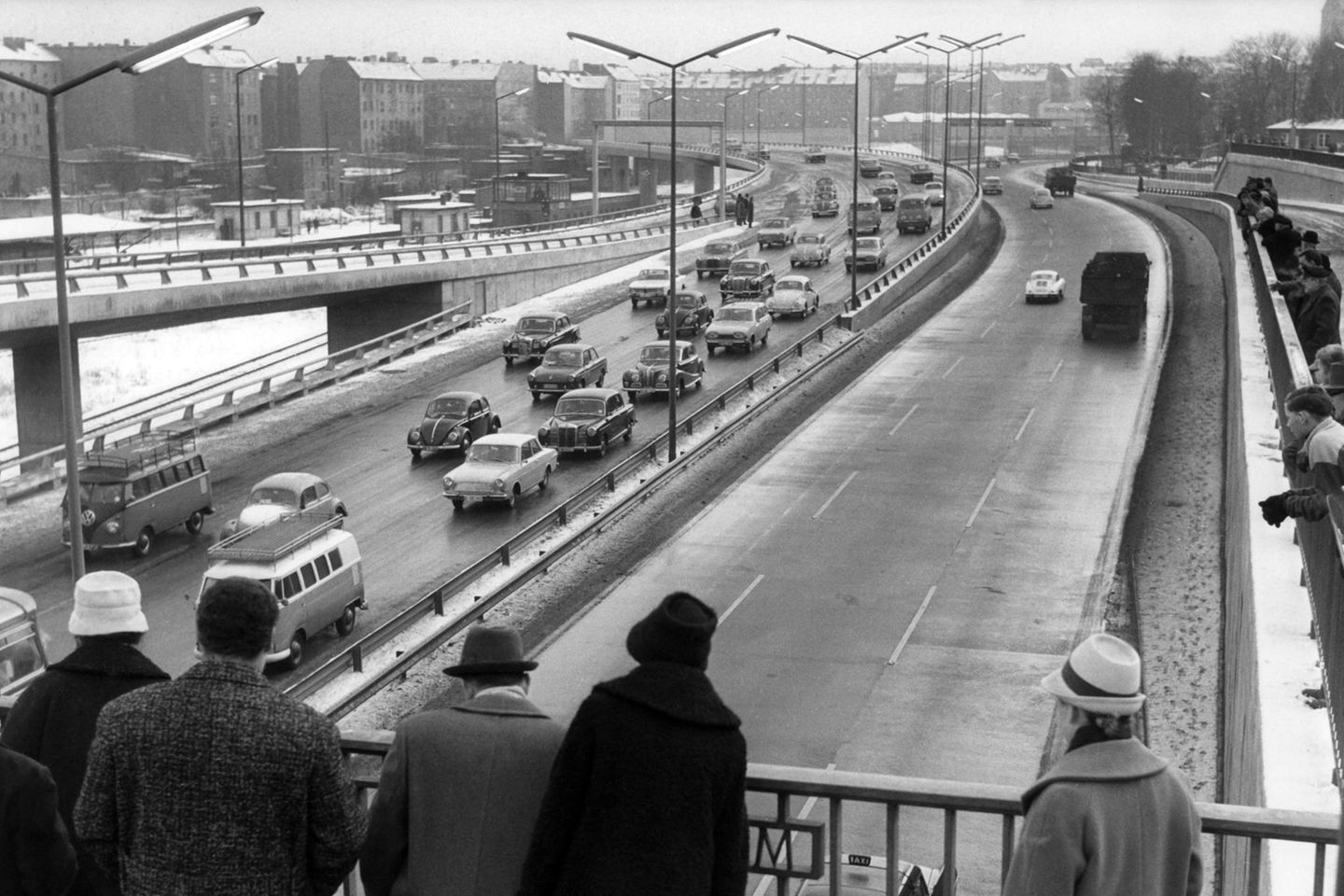 Schaulustige betrachten von einer Brücke aus eine neue Autobahn