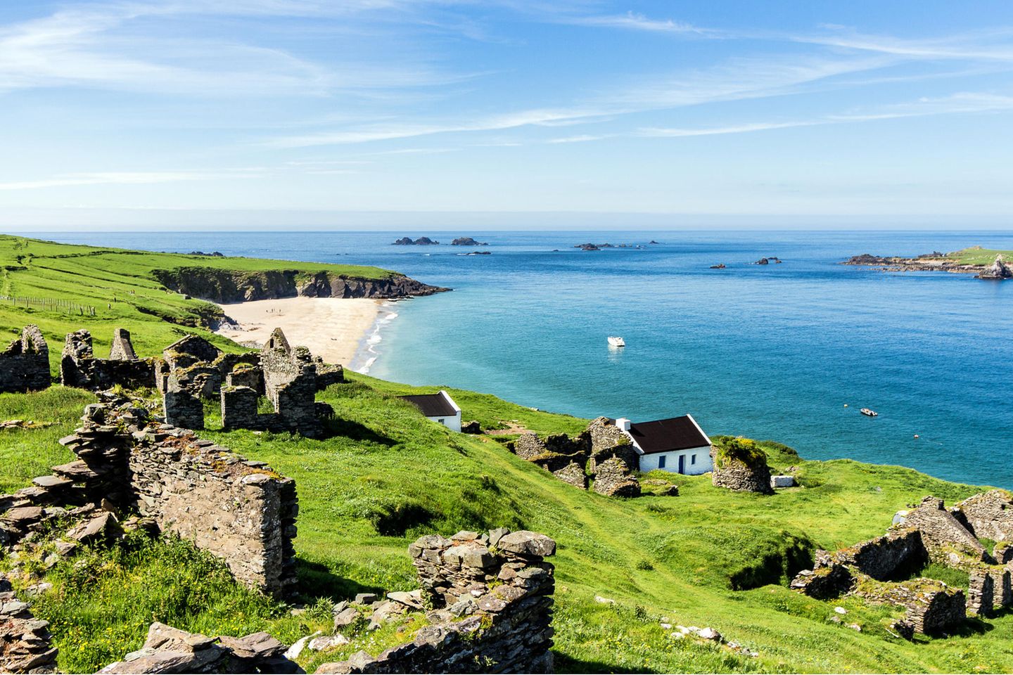 Küste mit sattem grün und klarem, blauem Wasser; ein paar vereinzelte Häuser