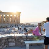 Amerikanische Touristin laesst sich vor der Akropolis in Athen fotografieren