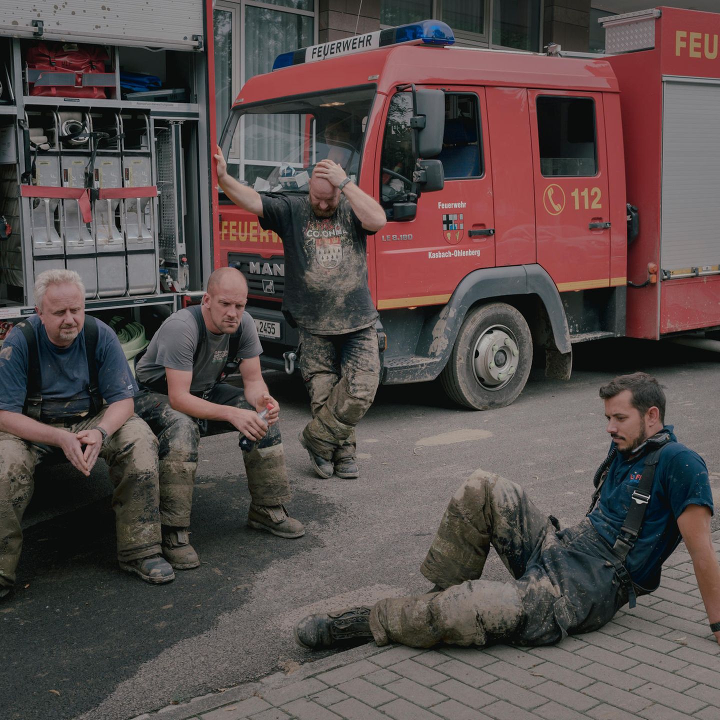 Freiwillige Feuerwehrleute machen vor einem Feuerwehrauto eine Pause