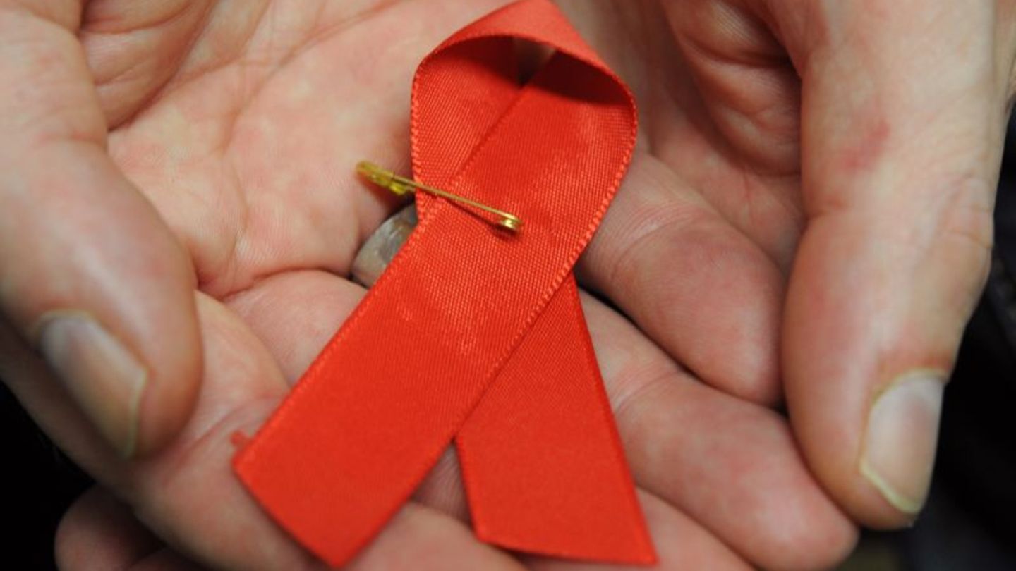 Ein mit dem HI-Virus infizierter Mann mit einer roten Schleife als Symbol der Solidarität mit HIV-Positiven und Aids-Kranken