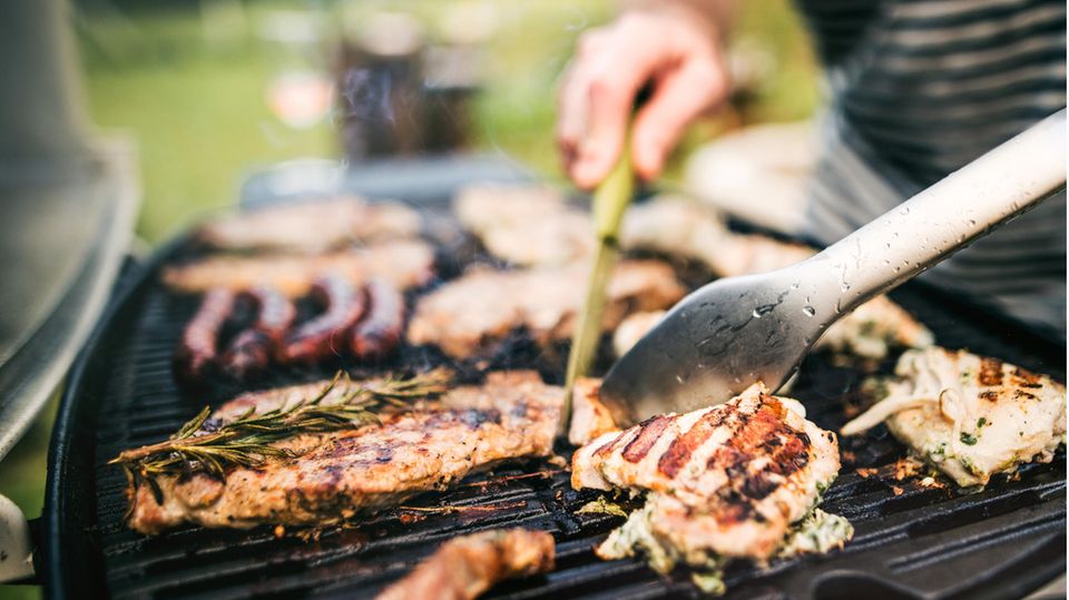 Fleisch liegt auf dem Grill und wird gewendet Fleisch liegt auf dem Grill und wird gewendet
