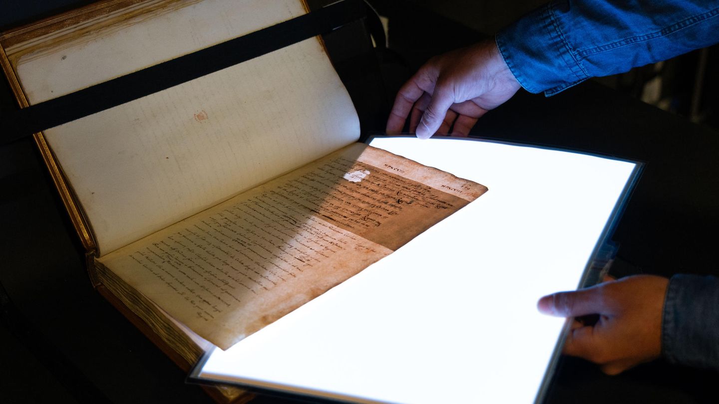 Seite eines alten Buchmanuskripts wird mithilfe einer starken Lichtquelle durchleuchtet