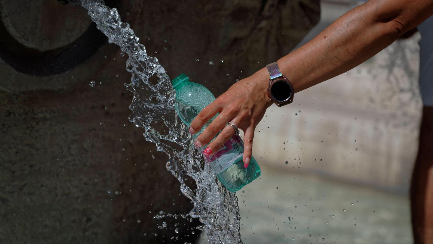 Eine Frau füllt an einem Brunnen in Rom eine Flasche auf