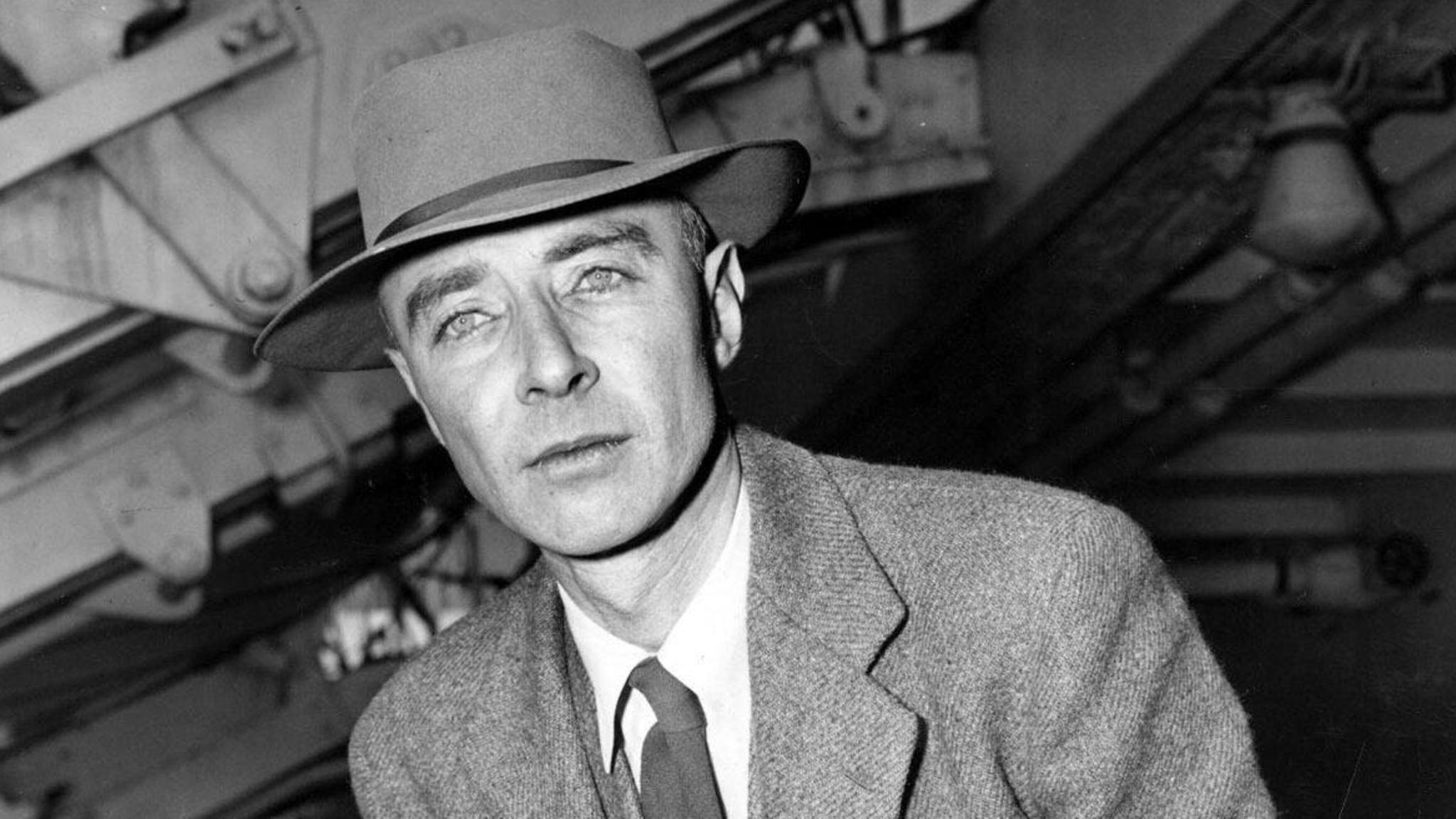 Robert Oppenheimer lehnt sich an einen Stuhl und hat eine Zigarette in der Hand