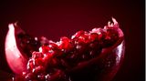 Ein aufgebrochener Granatapfel vor rotem Hintergrund