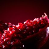 Ein aufgebrochener Granatapfel vor rotem Hintergrund