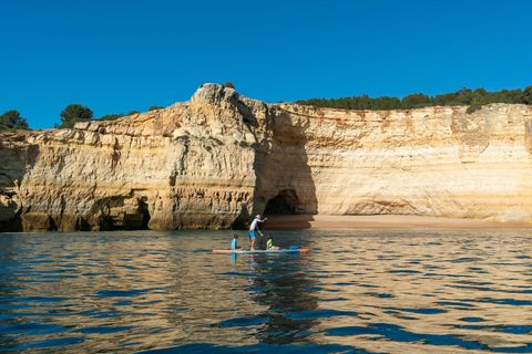 Ein Vater an der Algarve mit seinen Kindern im Meer auf einem SUP