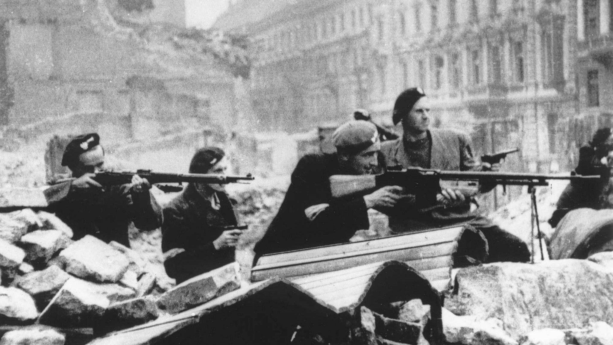 Polnische Soldaten in Warschau 1944 liegen mit ihren Gewehren im Anschlag hinter Trümmern