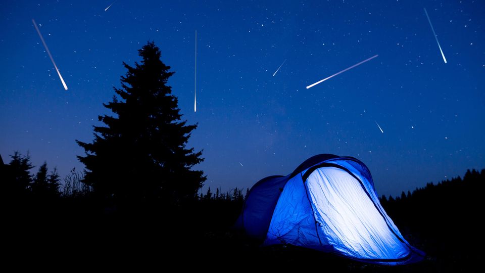 Sternschnuppen am Himmel über einem Zelt in der Nacht