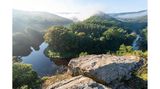 Panoramablick über einen sich windenden Fluss umgeben von Bäumen und tiefhängenden Wolken