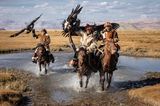Traditionelle Jäger sind mit Adlern auf ihren Pferden unterwegs