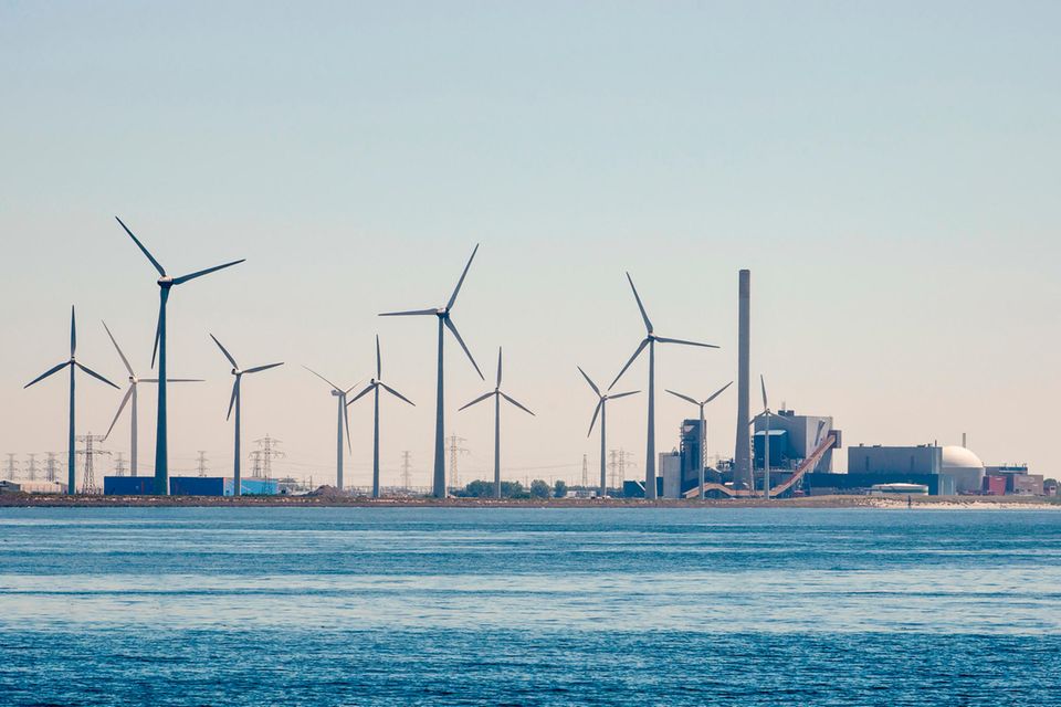 Windräder stehen neben einem Atomkraftwerk