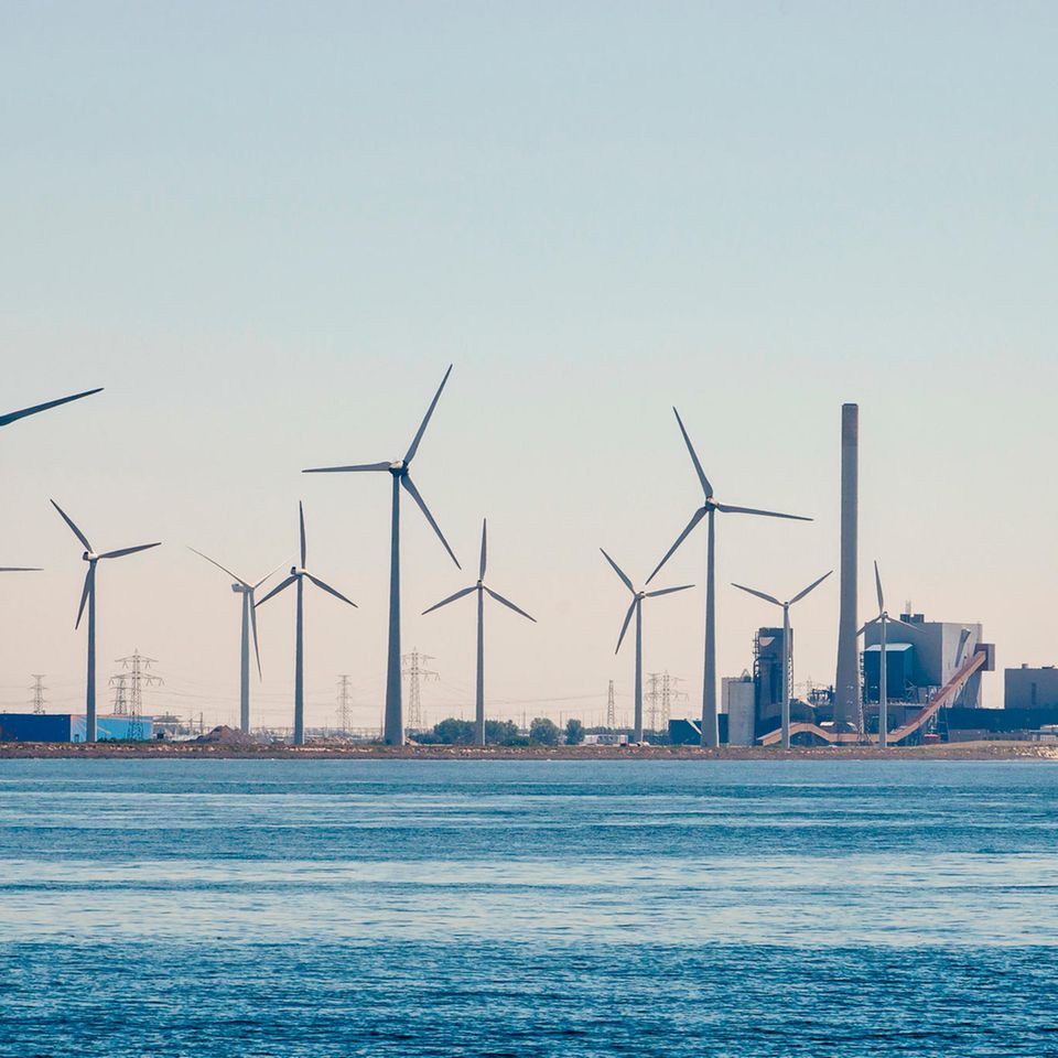 Windräder stehen neben einem Atomkraftwerk