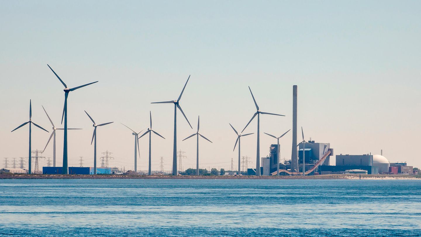 Windräder stehen neben einem Atomkraftwerk