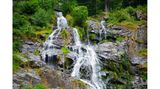 Breiter Wasserfall, der über einige Felsen in die Tiefe stürzt