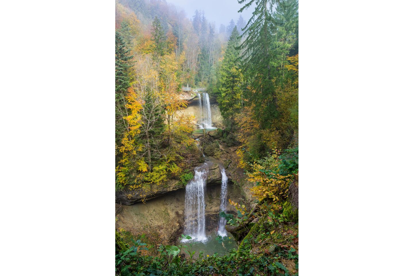 Blick auf einen Wasserfall mit herbstlich-verfärbten Bäumen rundherum