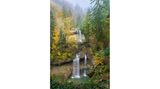 Blick auf einen Wasserfall mit herbstlich-verfärbten Bäumen rundherum
