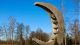 Der Holzturm hat die Form einer Mondsichel und steht direkt an einem See.