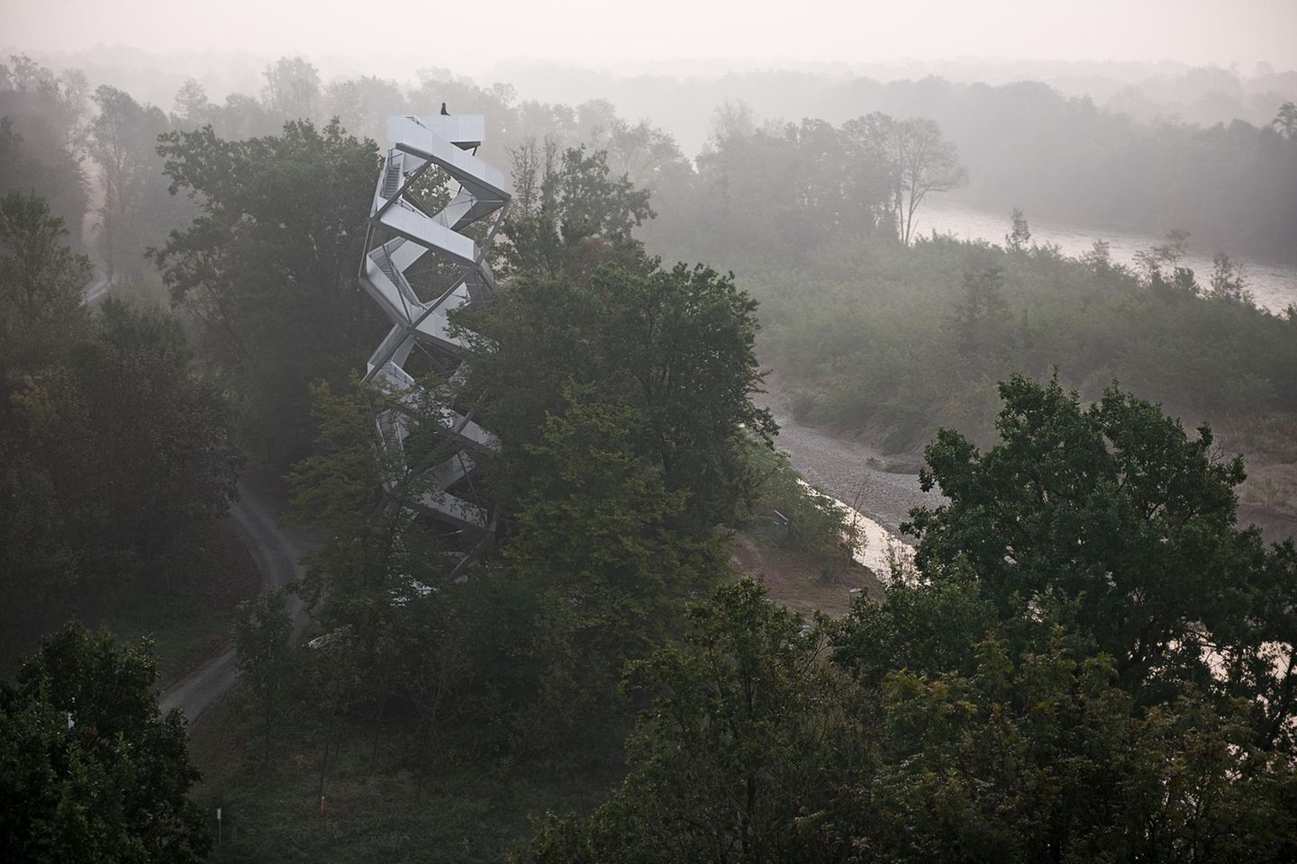 Im Nebel sieht man den Fluss Mur und ganz klein den hellen Turm, der an eine Doppelhelix erinnert.