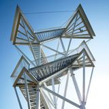 Man sieht nur die offenen Treppen und die Plattformen mit begehbaren Gittern auf den zwei Etagen vor dem tiefblauen Himmel.