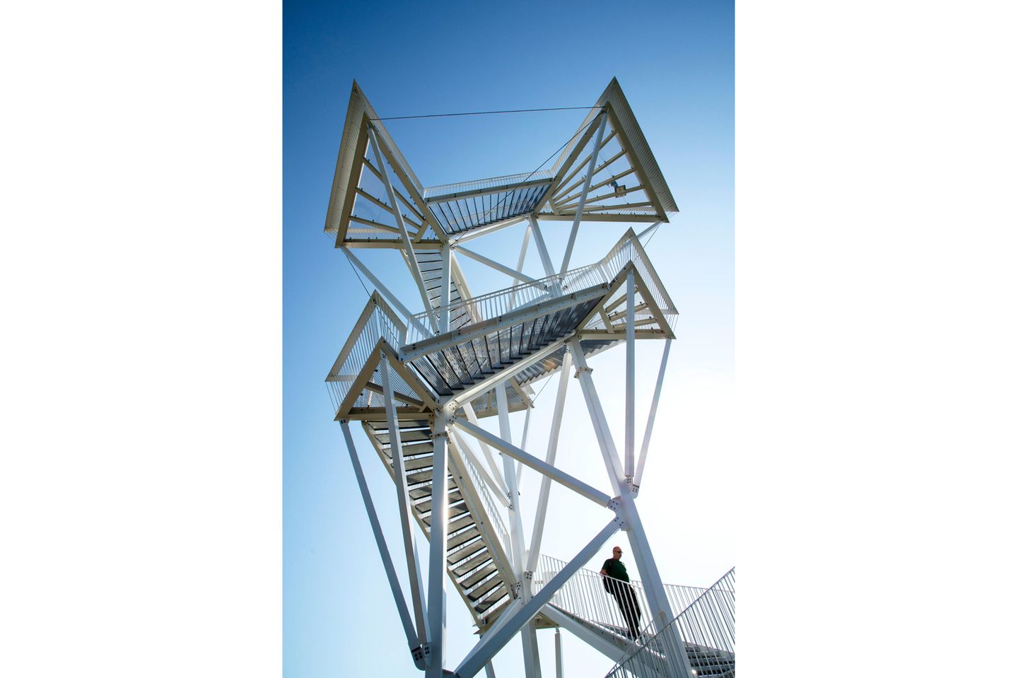 Man sieht nur die offenen Treppen und die Plattformen mit begehbaren Gittern auf den zwei Etagen vor dem tiefblauen Himmel.