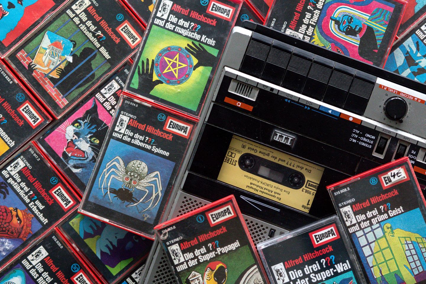 Zahlreiche Kassetten der Hörspielserie "Die drei Fragezeichen" liegen neben einem Kassettenrekorder.