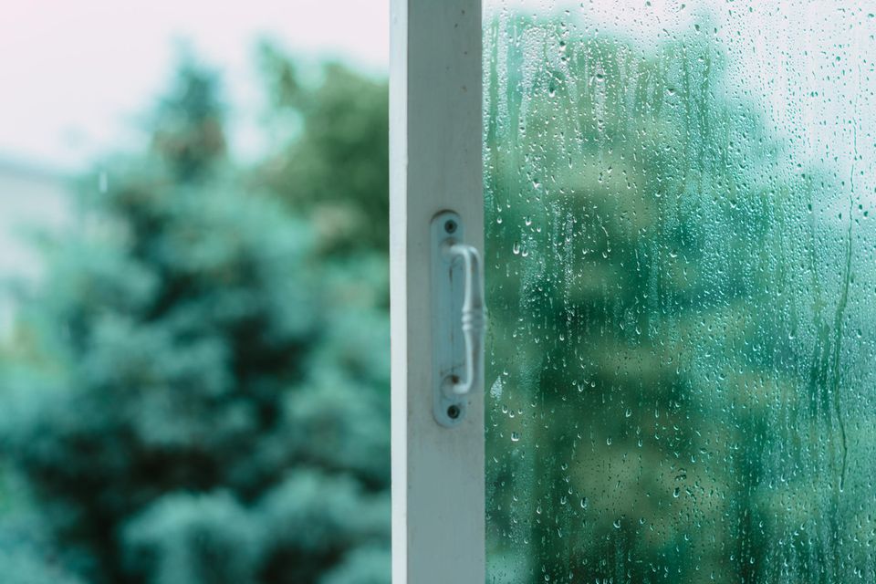 Offenes Fenster mit Regentropfen an der Scheibe