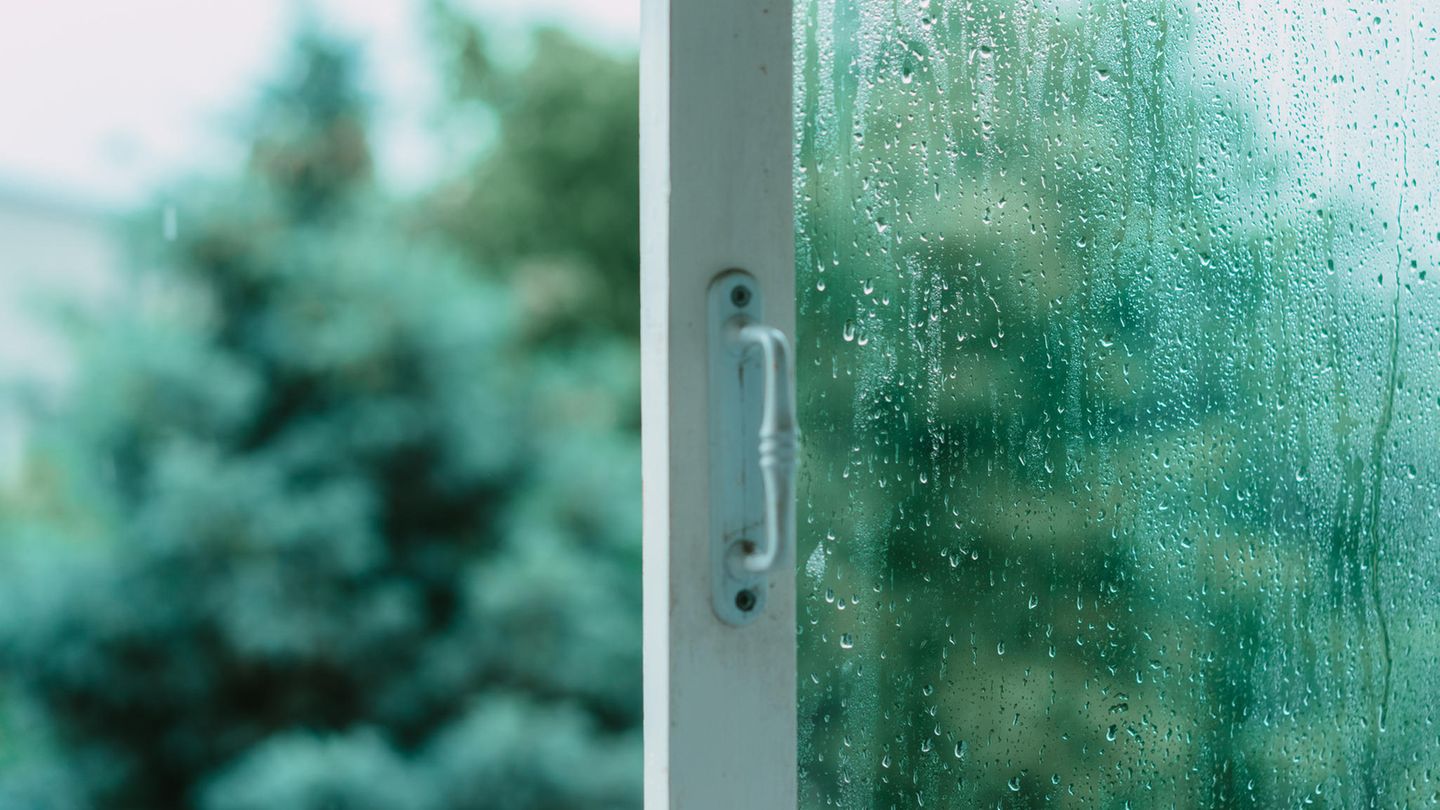Offenes Fenster mit Regentropfen an der Scheibe