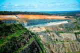 Der Cornwall Pit, ein gigantischer Tagebau im Südwesten Australiens, frisst sich seit den 1880er-Jahren durch die Landschaft. Dass die Gesteinsschichten auch Lithiumablagerungen beinhalten, wissen die Bergbauunternehmen seit über 50 Jahren. Lange förderten sie das Alkalimetall jedoch nur in kleinen Mengen: für die Keramikproduktion etwa. Seit jedoch die Weltmarktpreise für Lithium in die Höhe schießen, boomt auch das Geschäft der Minenbetreiber. Sie sprengen große Pegamititblöcke aus den Abbruchkanten: ein grobkörniges, granitähnliches Gestein, das mancherorts sechs Prozent Lithium beinhaltet. Nachdem die Gesteinsbrocken gebrochen und gemahlen wurden, werden sie chemisch aufbereitet. Auch am Ende dieser Produktionskette entsteht meist Lihtiumcarbonat, das zu großen Teilen nach China exportiert wird, wo es zu Lithiumhydroxid weiterverarbeitet und in Lithium-Ionen-Akkus verbaut wird. Der australische Tagebau steht wegen seiner Flächenverbrauchs, vor allem aber wegen seiner Treibhausgasemissionen in der Kritik: Laut dem Marktanalysten Roskill emittiert die Produktion einer australischen Tonne Lithium etwa 9 Tonnen Kohlendioxid.