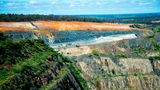 Der Cornwall Pit, ein gigantischer Tagebau im Südwesten Australiens, frisst sich seit den 1880er-Jahren durch die Landschaft. Dass die Gesteinsschichten auch Lithiumablagerungen beinhalten, wissen die Bergbauunternehmen seit über 50 Jahren. Lange förderten sie das Alkalimetall jedoch nur in kleinen Mengen: für die Keramikproduktion etwa. Seit jedoch die Weltmarktpreise für Lithium in die Höhe schießen, boomt auch das Geschäft der Minenbetreiber. Sie sprengen große Pegamititblöcke aus den Abbruchkanten: ein grobkörniges, granitähnliches Gestein, das mancherorts sechs Prozent Lithium beinhaltet. Nachdem die Gesteinsbrocken gebrochen und gemahlen wurden, werden sie chemisch aufbereitet. Auch am Ende dieser Produktionskette entsteht meist Lihtiumcarbonat, das zu großen Teilen nach China exportiert wird, wo es zu Lithiumhydroxid weiterverarbeitet und in Lithium-Ionen-Akkus verbaut wird. Der australische Tagebau steht wegen seiner Flächenverbrauchs, vor allem aber wegen seiner Treibhausgasemissionen in der Kritik: Laut dem Marktanalysten Roskill emittiert die Produktion einer australischen Tonne Lithium etwa 9 Tonnen Kohlendioxid.