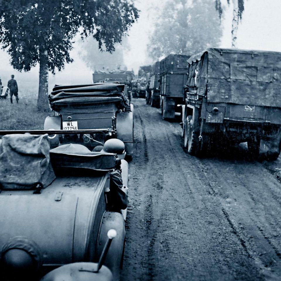Deutsche Soldaten fahren in Autos und Militärlastern eine Feldstraße entlang