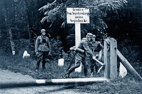 Ein deutscher Soldat schlägt mit einer Axt auf einen Schlagbaum an der deutsch-polnischen Grenze ein