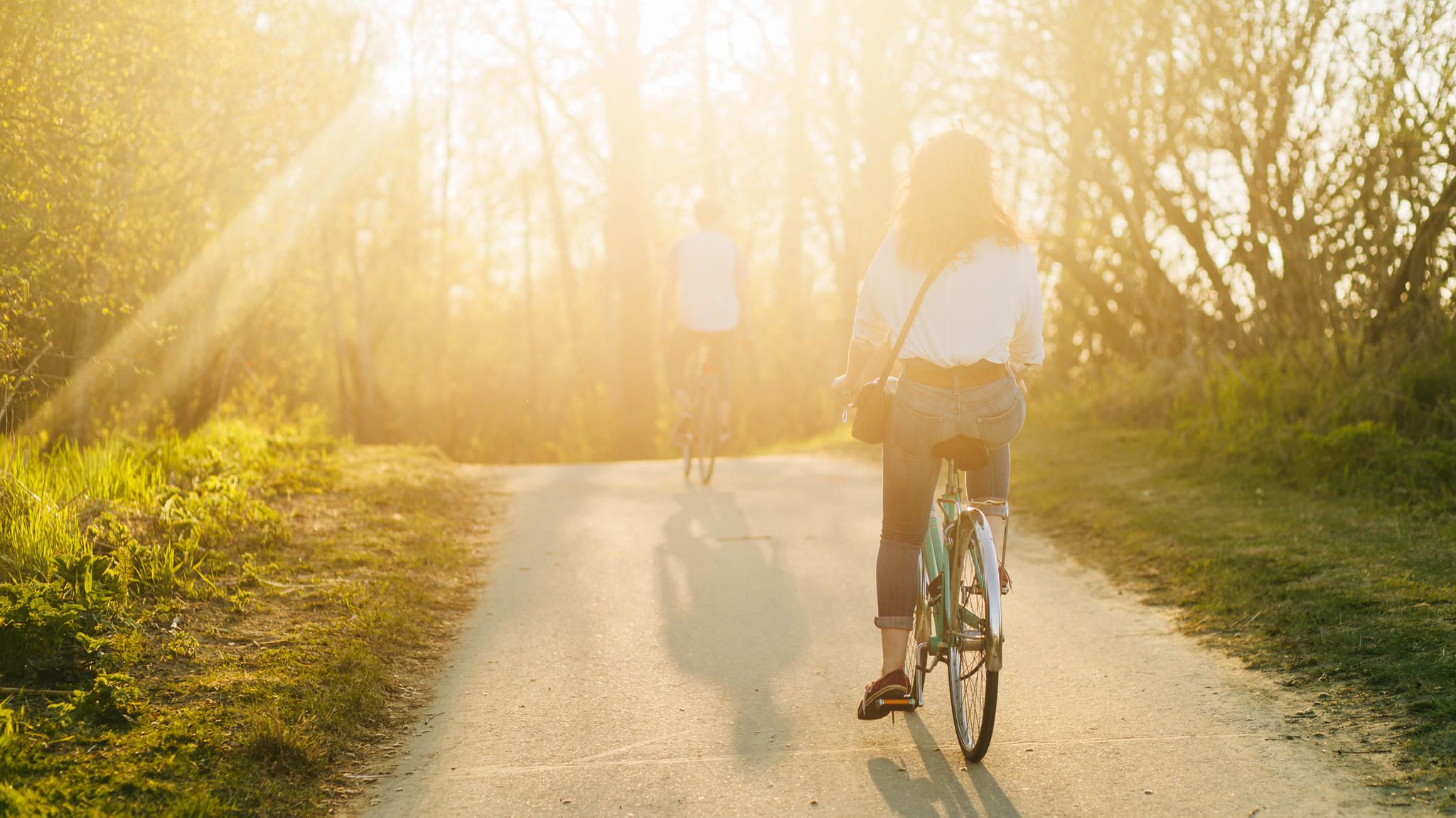 Zwei Fahrradfahrer fahren in den Sonnenuntergang Zwei Fahrradfahrer fahren in den Sonnenuntergang
