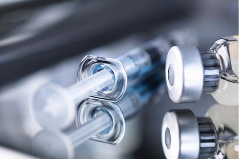 Eine Spritze und ein Vakzin liegen auf einem Tisch