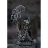 Ein Bartkauz steht auf einer betenden Engelsstatue aus verwittertem Stein.