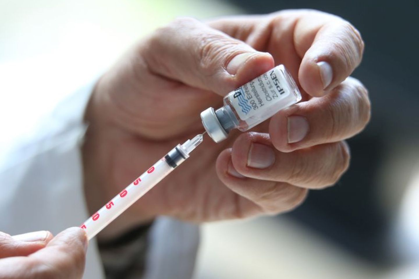 Arzt zieht mit einer Spritze den Botox-Stoff aus einem kleinen Gefäß