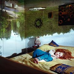 Schlafende Frau mit Traumwelten im Hintergrund.