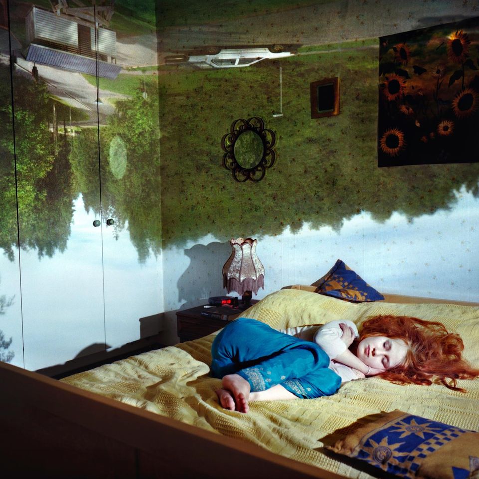 Schlafende Frau mit Traumwelten im Hintergrund.