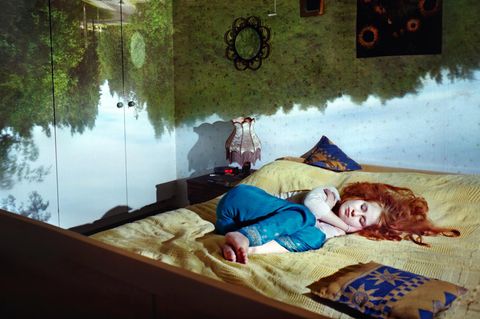 Schlafende Frau mit Traumwelten im Hintergrund.