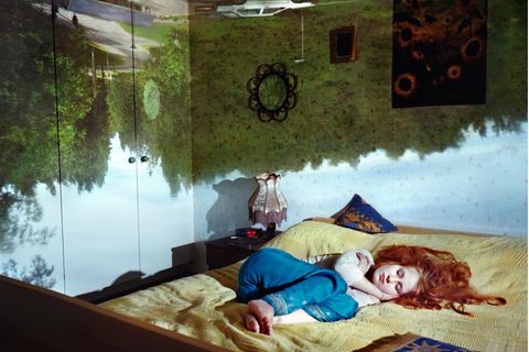 Schlafende Frau mit Traumwelten im Hintergrund.