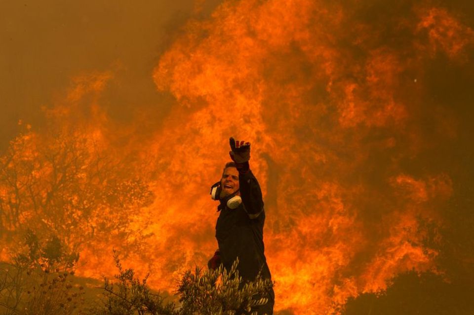 Ein Feuerwehrmann kämpft im griechischen Dorf Hasia nahe Athen gegen ein Flammenmeer. Foto: Marios Lolos/XinHua/dpa