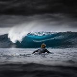 In Westaustralien fotografierte Jarvis Smallman diesen Surfer und eine sich brechende, blau schimmernde Welle, während Regenwolken aufziehen: erster Platz in der Kategorie Young Ocean Photographer of the Year