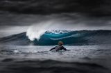 In Westaustralien fotografierte Jarvis Smallman diesen Surfer und eine sich brechende, blau schimmernde Welle, während Regenwolken aufziehen: erster Platz in der Kategorie Young Ocean Photographer of the Year