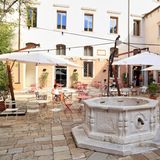 Alter Brunnen, Sonnenschirme und Tische im Innenhof des ehemaligen Klosters.