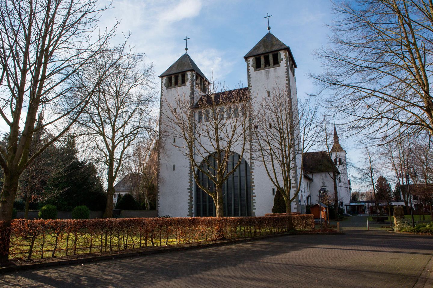 Abtei Varensell, bei Rietberg in Nordrhein-Westfalen Kirche mit zwei Türmen und großer Portaltür zwischen Bäumen. Der Himmel ist blau.