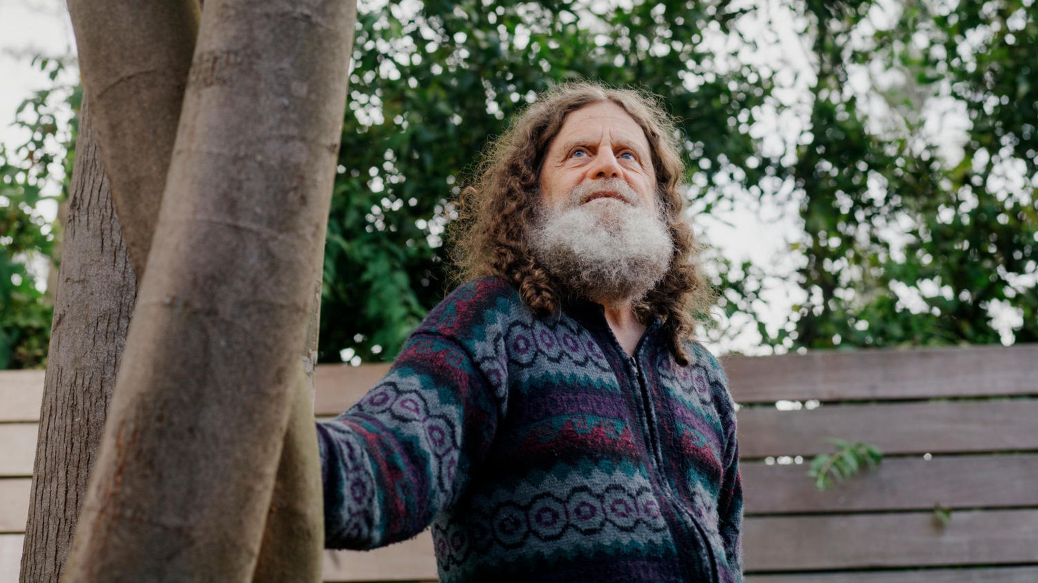 Neurowissenschaftler Robert M. Sapolsky steht leicht angelehnt an einem Baum.