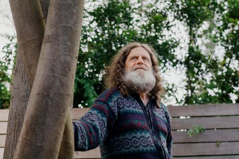 Neurowissenschaftler Robert M. Sapolsky steht leicht angelehnt an einem Baum.