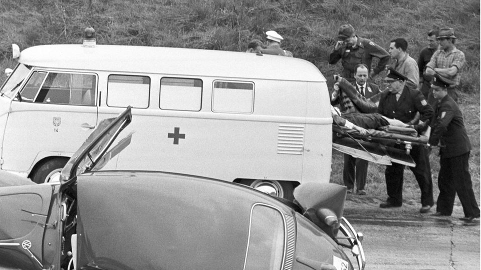 Retter schieben in den 1960er Jahren einen Verletzten auf einer Trage in einen Krankenwagen